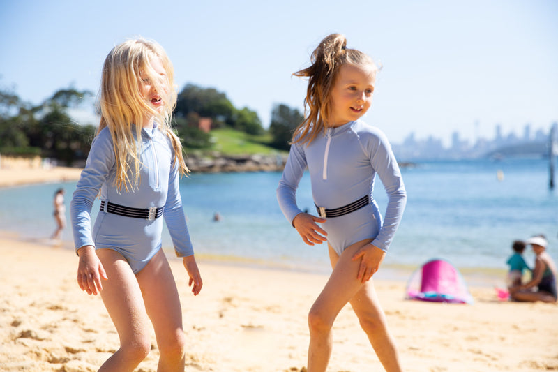 Two girls on beach wearing the Blue Lagoon One Piece Suit with belt