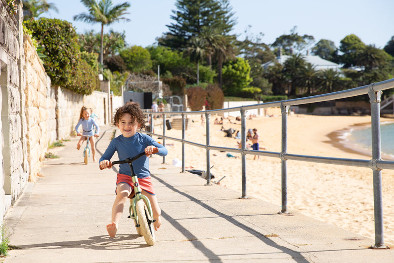 Boy On Bike Wearing Rose Swim Shorts With Blue Detail 